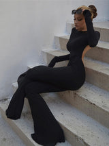 Woman posed in a seated position leaning back in the black sexy backless jumpsuit