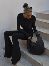 Woman posed in a seated position in the black sexy backless jumpsuit