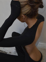 Woman posed in a seated position in the black sexy backless jumpsuit